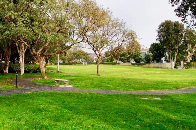 Seabridge Townhomes park with trees and a sidewalk on a cloudy day.