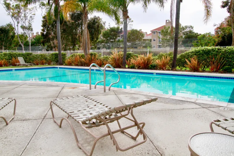 Seabridge Townhomes pool with deck chairs and a table on a cloudy day.