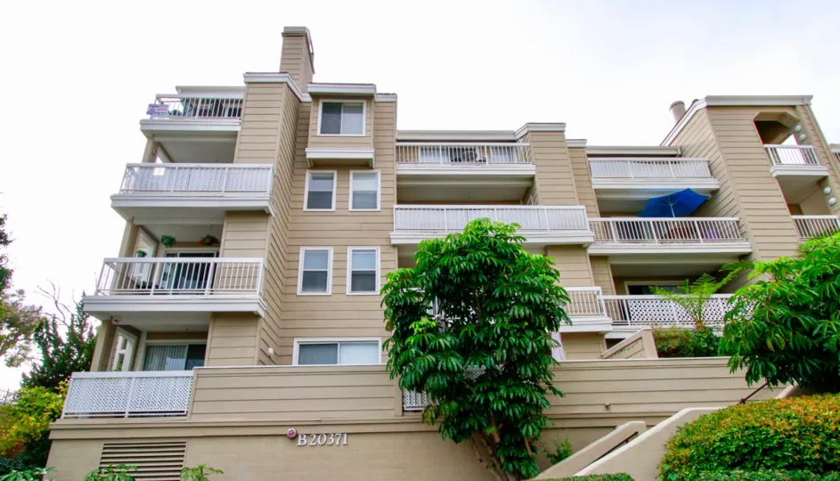 Four story Seabridge Villas building with balconies and a staircase on a cloudy day.