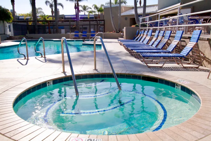 Seabridge pool and hot tub with deck chairs and palm trees.