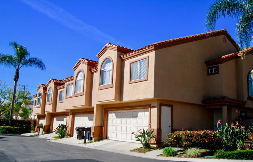 Seacliff Palms building with garages and trash can on a sunny day.