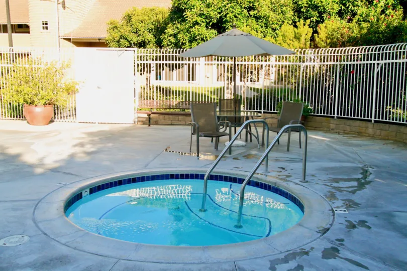 Seagate hot tub with deck chairs and an umbrella around it.