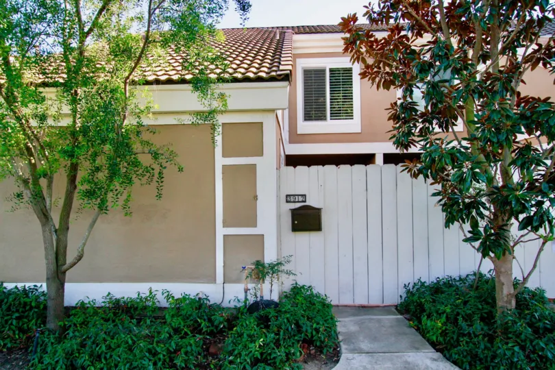 Condo unit with white fence and limited landscaping located in Huntington Beach, CA