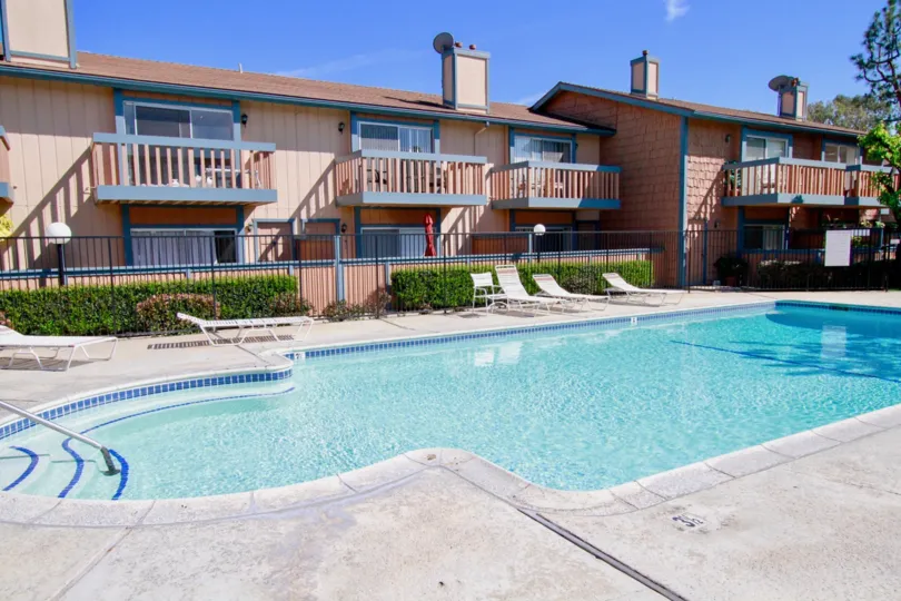 THE BUILDINGS WITH SWIMMING POOL AND THREE SEPARATED HOUSES SOME SITTING CHAIRS NEAR TO THE POOL SOME PLANTS NEAR TO THE HOUSES.