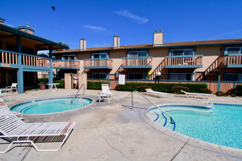 Seascape pool and a hot tub with deck chairs and a table.