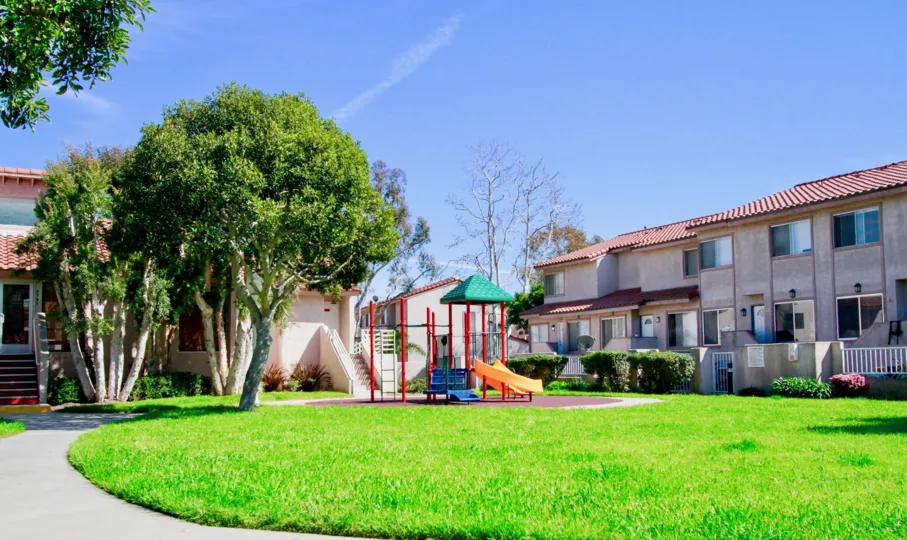 Seaside Village park with a playground and trees on a sunny day.