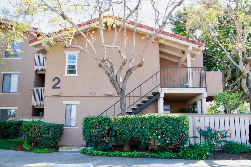 THE BUILDING WITH THE NUMBER SIGN TWO AND A STEPS ALSO BESIDE THE OUTSIDE BUILDING SOME TREE PLANTS NEAR TO THE HOUSE.