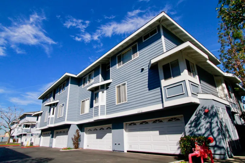 Townhomes ontop of garages that are three stories tall and are bluish grey.