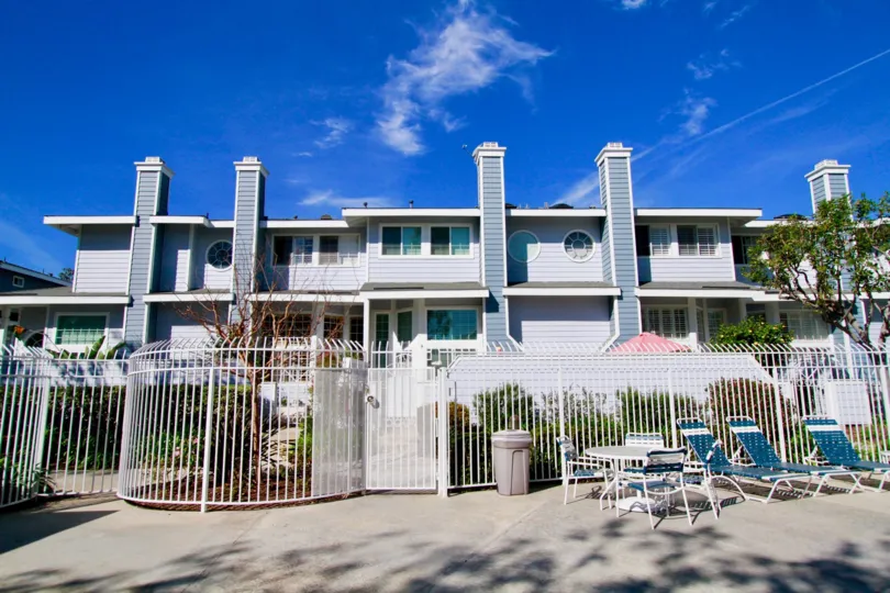 The building in the Seawind Cove is look like a palace with fencing, chairs, tables and trees.