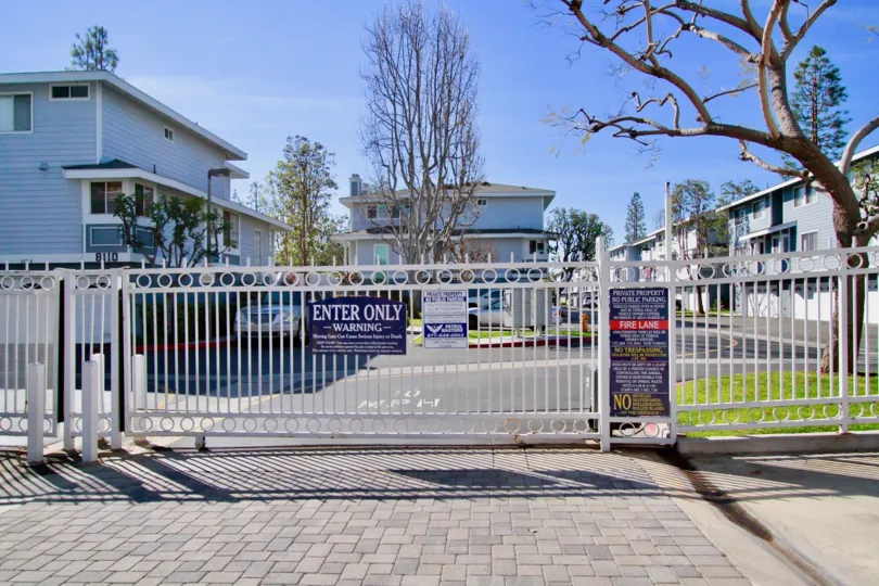 Seawind Cove metal gate with a sign in front of it on a sunny day.