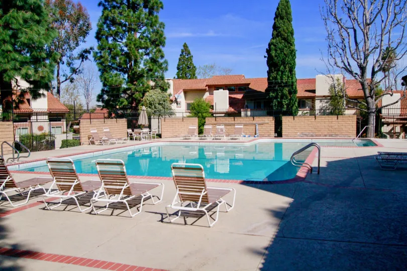 Community pool in residential community located in Huntington Beach California on a sunny day with lounge chairs and no one in the pool