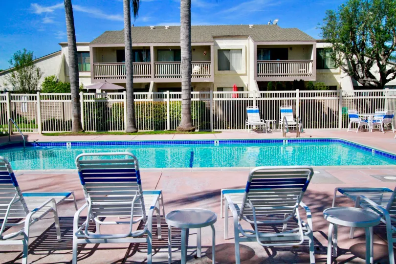 The Tamarack Village pool with deck chairs and tables enclosed by a fence.