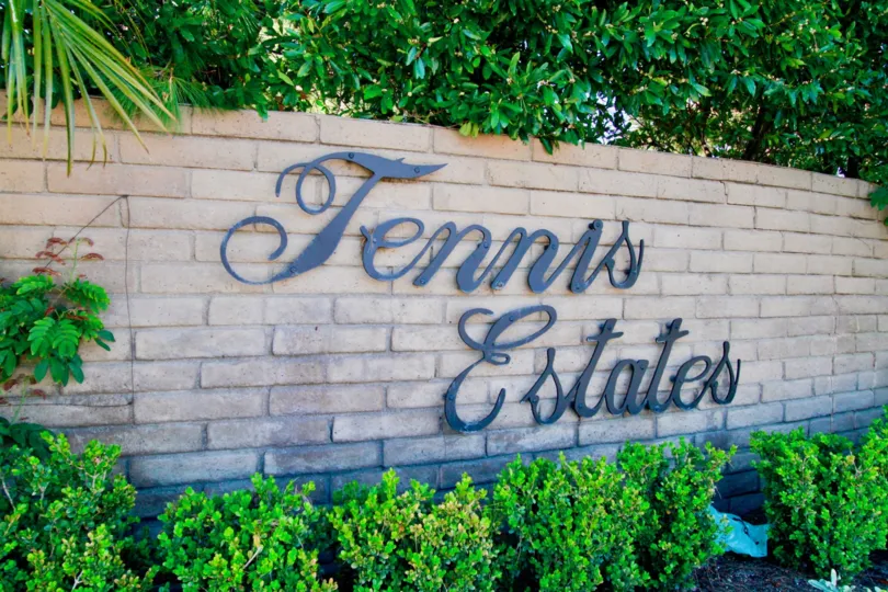 Front sign at Tennis Estates with nice shrubs and plants surrounding the sign.