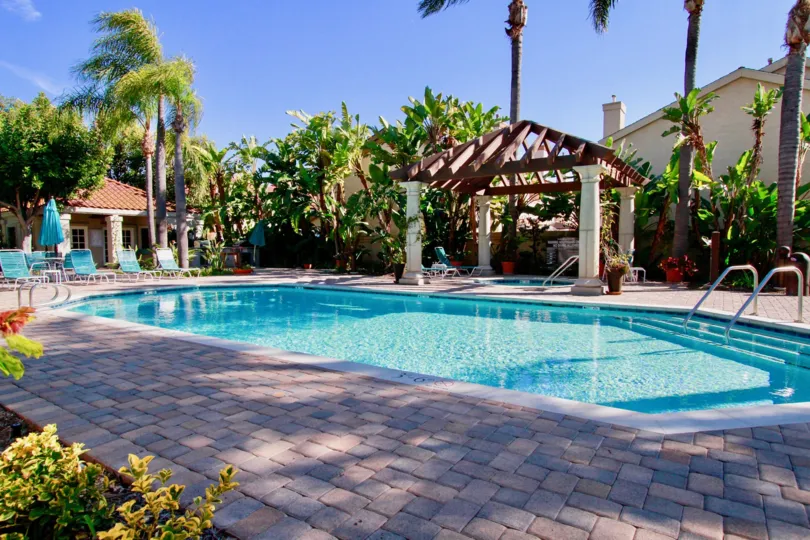 Tiara De La Pacifica pool with deck chairs and palm trees on a sunny day,