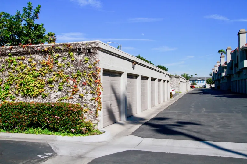 A sunny day at Tiara De La Pacifica Townhomes in Huntington Beach with vines growing on the garage wall