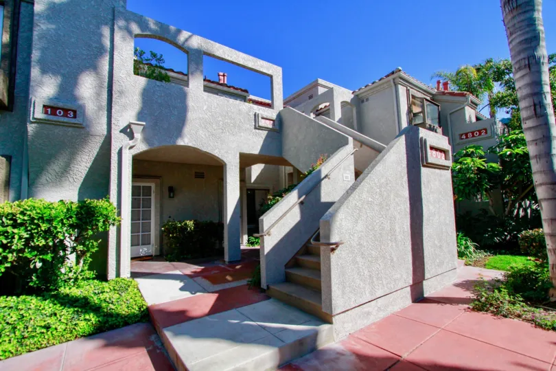 Tiara De La Pacifica apartments with a staircase and bushes on a sunny day.