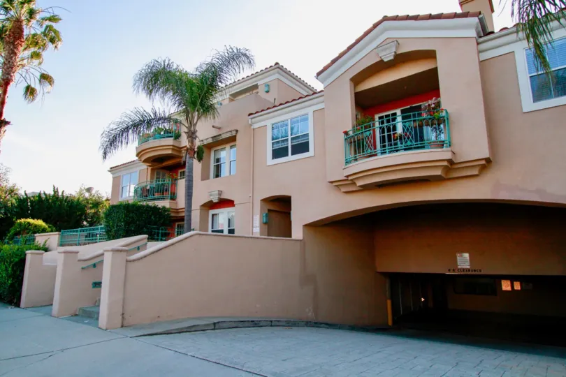 Villa Milano apartments with balconies and a parking garage on a sunny day.