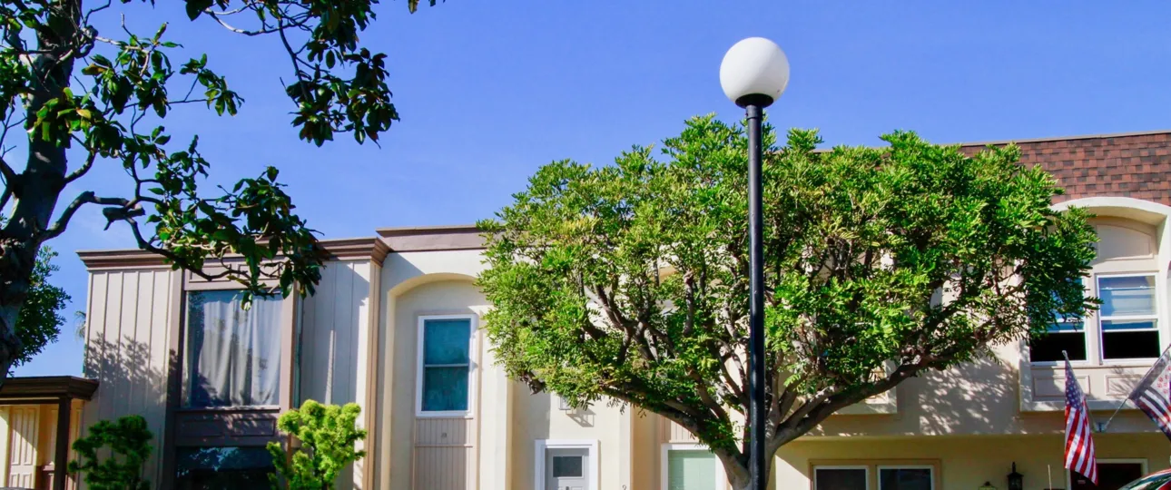 A BUILDING WITH THE LAMP AT OUTSIDE AND SOME TREES ALSO SURROUNDING THE HOUSE AND A ROOF TOP ALSO AVAILABLE.