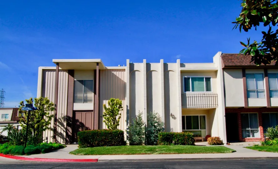 multiple townhomes with well kept landscaping and vegetation on a sunny day