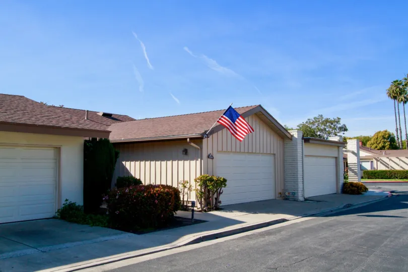 Villa Pacifica homes with a American flag and garages on a sunny day.