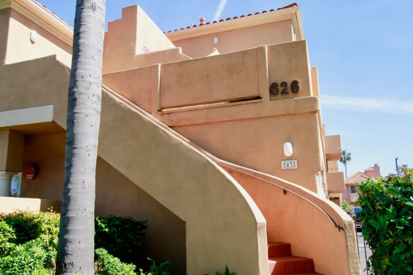 Villas Del Mar staircase with a palm trees and bushes on a sunny day.