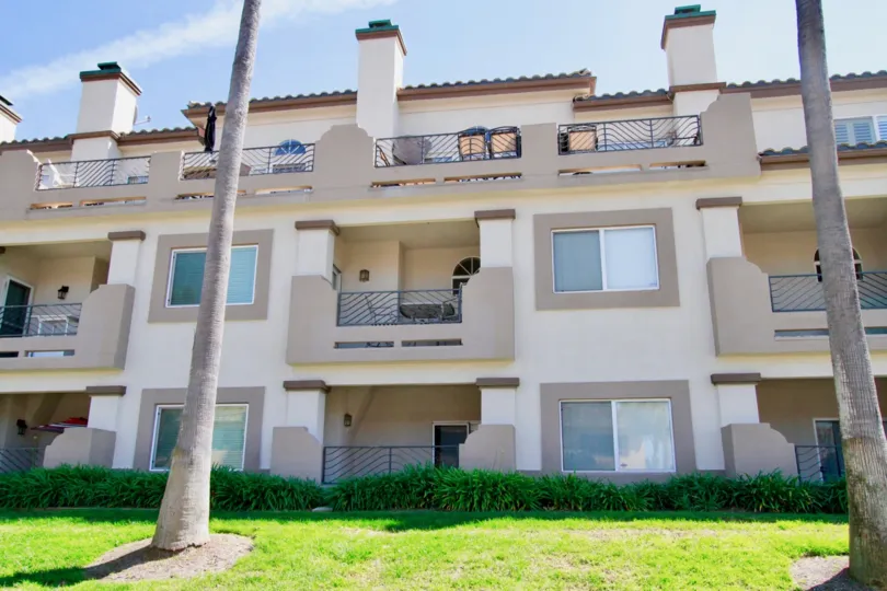 Excellent view of a lawn in front of Villas with balconies and palm trees in Vista of Catalina of Huntington Beach