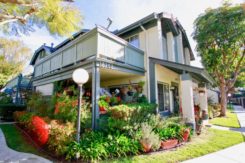 THE BUILDING LOOKS LIKE A BUNGALOW WITH A NUMBER AND A LAMP SOME FLOWERS ALSO NEAR TO THE BUILDING.
