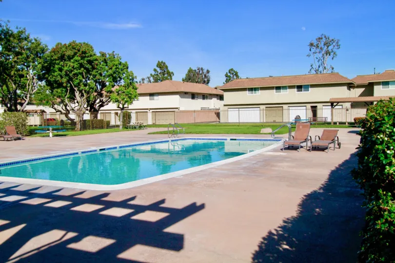 A sunny day in the Yorktown villas with swimming pool, trees, chairs, lawns and also with nearby houses.