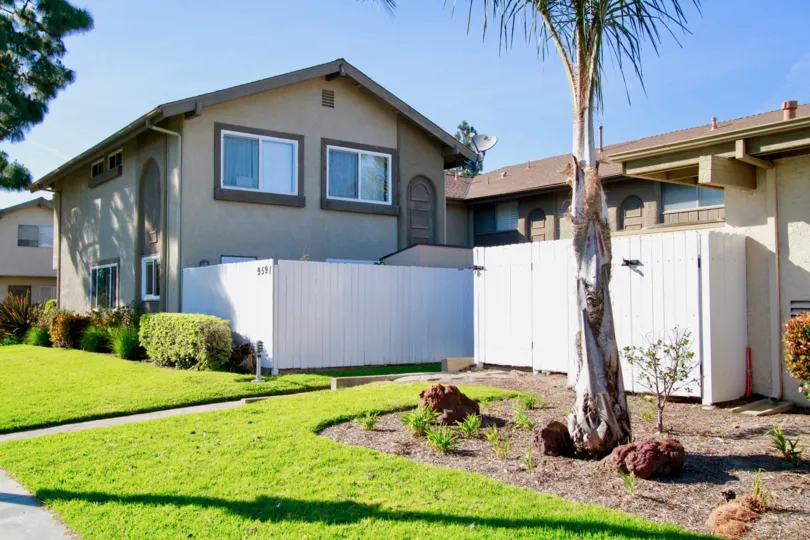 THE HOUSE WITH DOOR CLOSED AND WINDOWS CLOSED AND A TREES ALSO AVAILABLE AND THE GRASS AND PLANTS ALSO AVAILABLE IN FRONT OF THE PLACE.