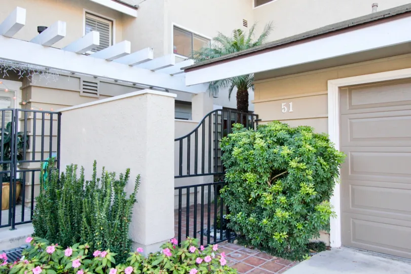 THIS IS FRONT VIEW OF THE HOUSE WITH NUMBER ON THE WALL, PLANTS WITH FLOWERS ARE THERE IN THE IRVINE CITY