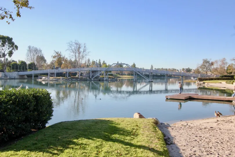 A sunny day in Arborlake with a bridge above a river or a lake and trees.
