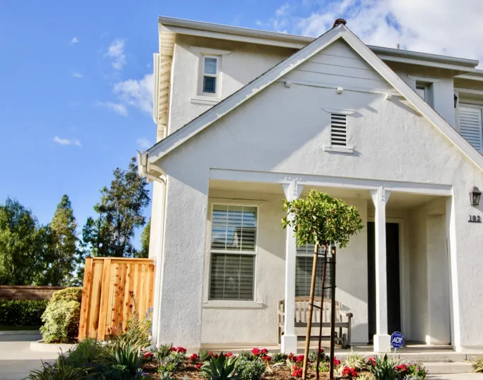 The front side of white color Arden Square with open door and flowering plants in front side