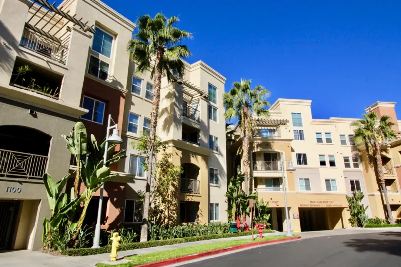 A sunny day in Avenue One with tall buildings with balconies and tall palm trees next to them