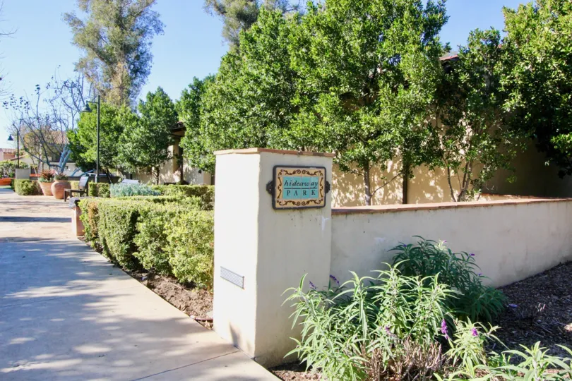 THE ENTRANCE WAY TO THE APARTMENT WHICH IS IN IRVINE, THAT SHOWS THE LOT OF PLANTS, TREES, NAME BOARD ON THE WALL ARE THERE