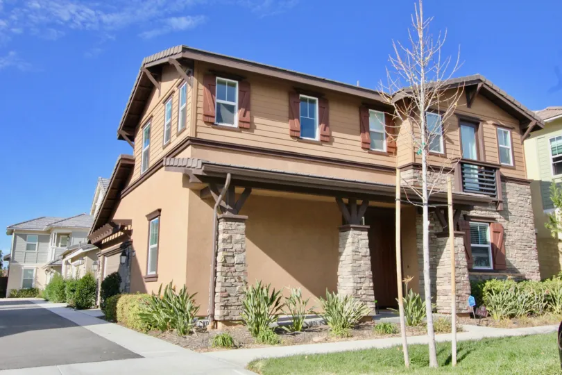 A sunny day in Birch Trail, with a large house with a balcony.