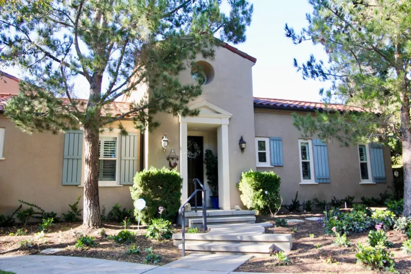 THE FRONT VIEW OF THE HOME WITH TREES, PLANTS, LAMPS ON EACH SIDE ARE SHOWN IN THE CITY OF IRVINE
