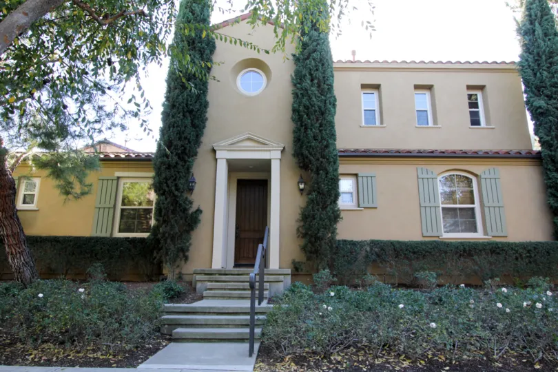 THE FRONT VIEW OF THE HOME WITH LOT OF PLANTS, TREES ON EACH SIDE, GLASS WINDOWS ARE THERE IS PLACED IN THE CITY OF IRVINE