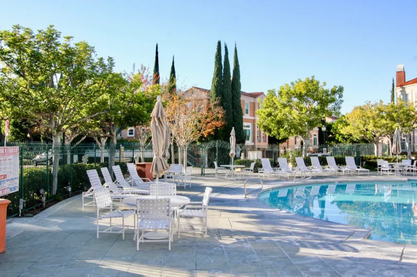 THE BEAUTIFUL SWIMMINGPOOL WITH LOT OF CHAIRS, SHOWS LOT OF TREES WHICH IS LOCATED IN THE CITY OF IRVINE