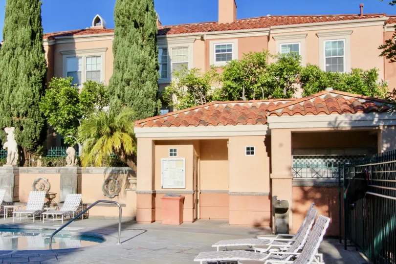 Pool with white sun chairs and surrounded by an apartment complex