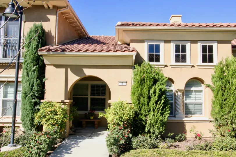 THE FRONT VIEW OF HOUSE WITH PLANTS, TREES, LAWN, GLASS WINDOWS ARE SITUATED IN CORTILE