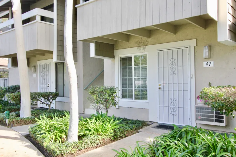 A sunny day in Irvine Springs with light colored houses with balconies and white doors.