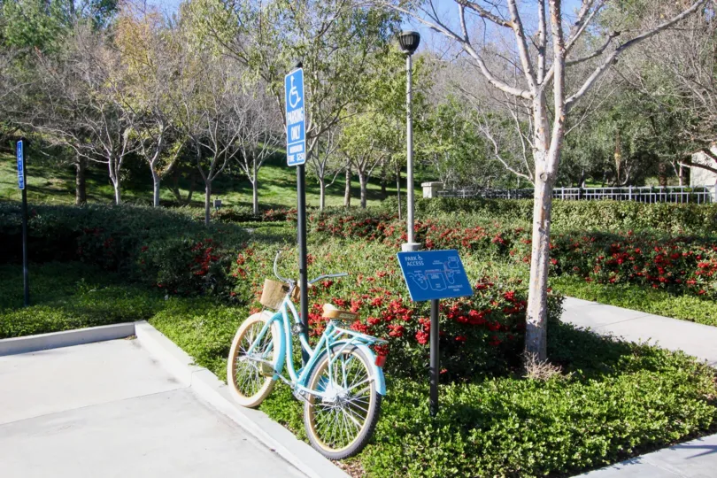 A sunny day showing a blue bicycle leaning against a sign in a park in the Ivy Wreath community of Irvine California.