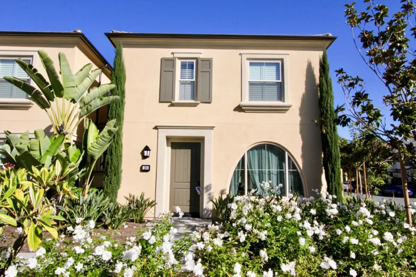 THE FRONT OF THE HOUSE, MANY PLANTS WITH FLOWERS, TREES ARE THERE WHICH IS IN IRVINE CITY