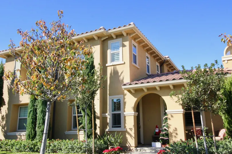 A clear sunny day showing the trees and landscape in front of a spanish style home in the La Casella community of Irvine California.