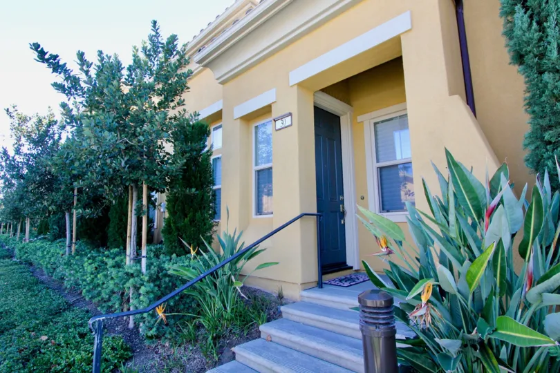 THE FRONT VIEW OF HOUSE WITH LOT OF PLANTS, AND TREES ON EACH SIDE WHICH IS LOCATED IN IRVINE CITY