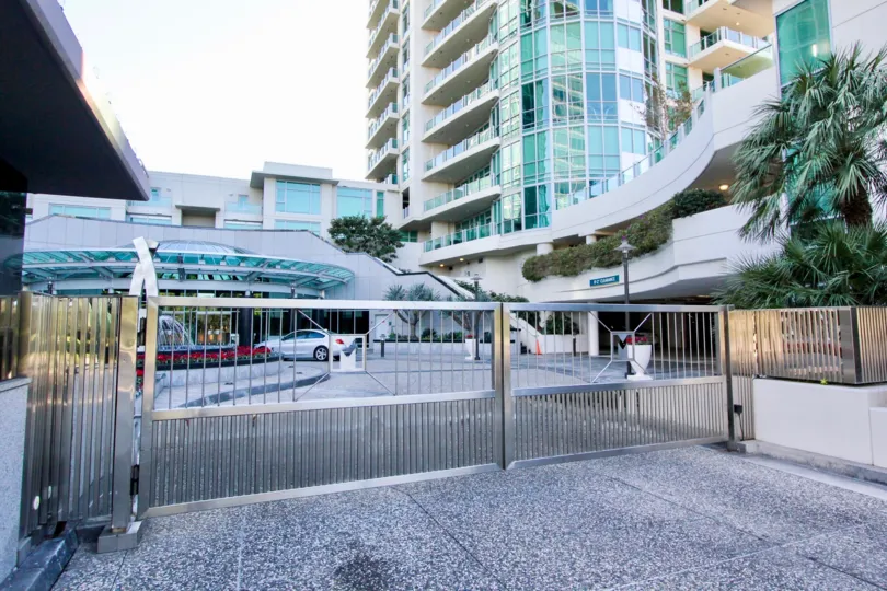 A gated driveway in the Marque at Park Place community with tall buildings.