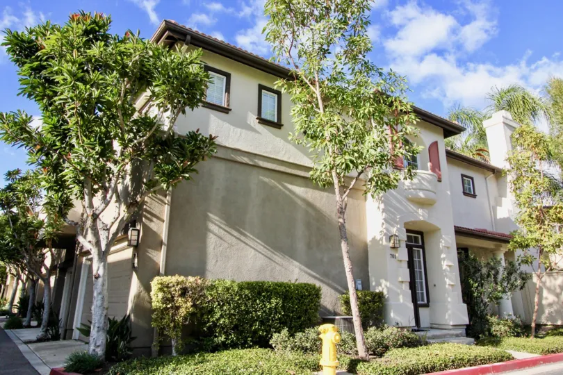 A sunny day in Northwood Pointe, with a large house with light plaster and dark window frames, surrounded by trees.