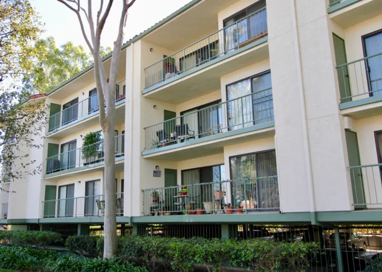 Building in Orangetree Terrace with balconies with potted plants and trees and hedges next to it.