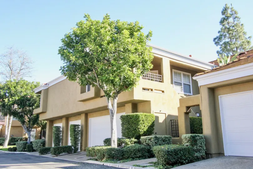A two story brown painted home with white garage door at Oxford Court in Irvine CA