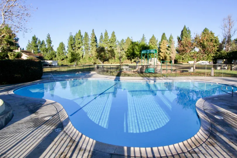 In sunny day of Park Homes with swimming pool with tall trees and meadows